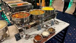 A tase of India in foreground. Mixed veggies and pasta in background.