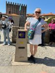 Lynn standing beside the yellow arrow and stylized scallop shell that guide hikers along the Camino trail. We start in hot sunny weather…